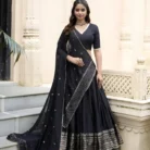 Close-up detail view of black designer lehenga choli showing mirror work and embroidered dupatta embellishments