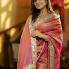 Model wearing Khusika brand premium designer saree in dual-tone pink and orange with heavy mirror work border.